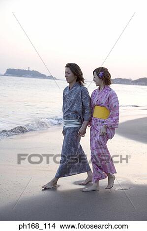 Couple taking a walk by the beach during sunset View Large Photo Image Picture - Couple taking a walk by the beach during sunset. Fotosearch