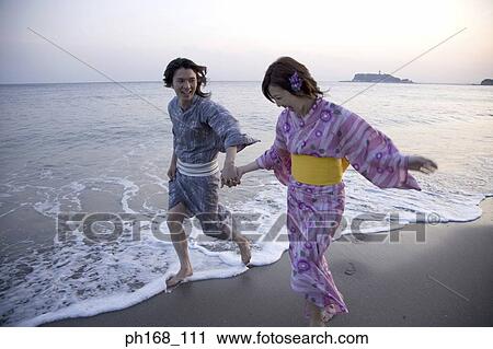 Stock Image - Couple walking by the beach, barefoot. Fotosearch
