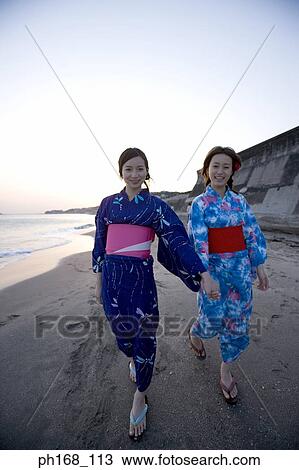 Stock Image - Two women walking along the beach. Fotosearch