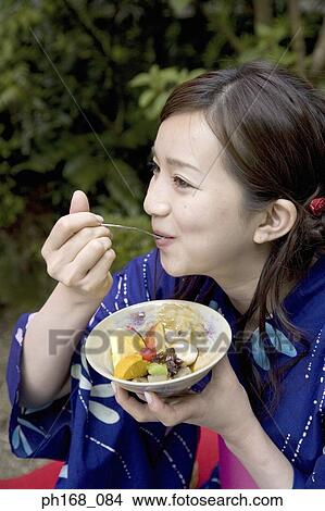 Picture - Woman in kimono enjoying dessert in the garden. Fotosearch