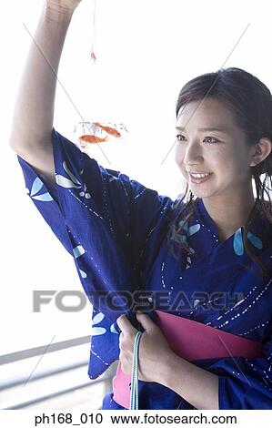 Stock Image - Woman in kimono holding a plastic bag with goldfish. Fotosearch