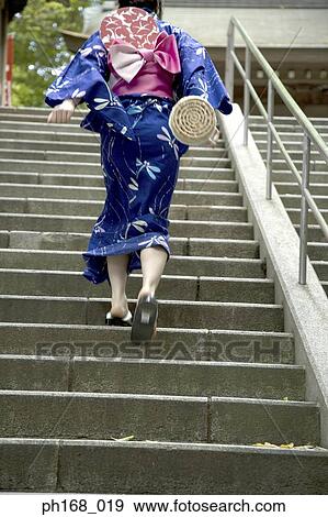 Stock Photo - Woman in kimono running up the stairs, rear view. Fotosearch