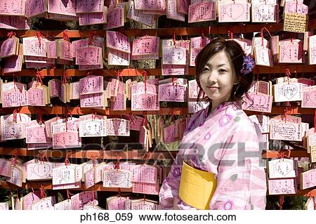 Woman in kimono standing by a panel of fortune slips View Large Photo Image Stock Photo - Woman in kimono standing by a panel of fortune slips. Fotosearch