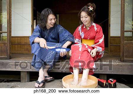 Stock Image - Man looking at woman soaking her feet in a tub. Fotosearch
