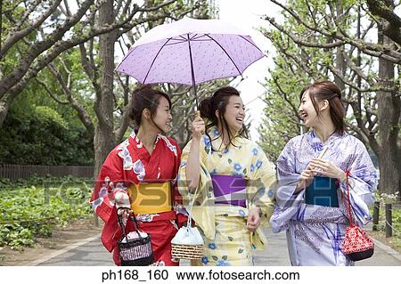 Stock Image - Three women taking a stroll down the park. Fotosearch