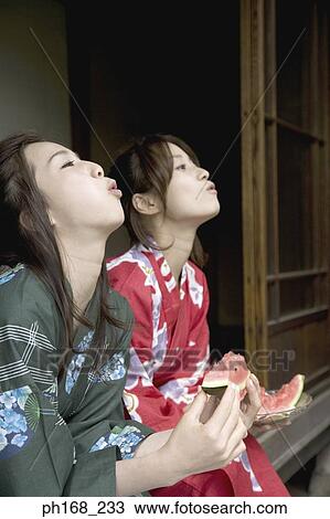 Two women eating water melon by the corridor View Large Photo Image Stock Image - Two women eating water melon by the corridor. Fotosearch