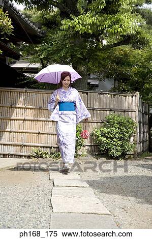 Stock Photography - Woman in kimono walking along pathway. Fotosearch