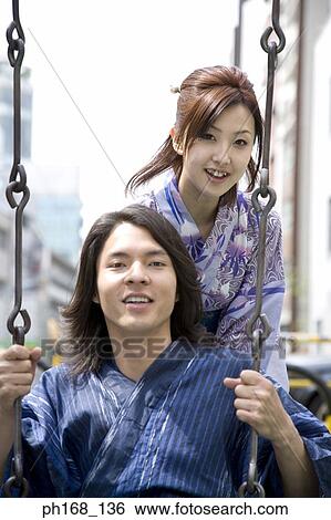 Woman pushing man on a swing View Large Photo Image Stock Photograph - Woman pushing man on a swing. Fotosearch