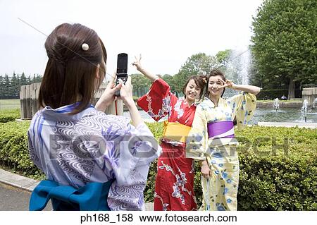 Woman taking picture of her friends with mobile phone View Large Photo Image Stock Photo - Woman taking picture of her friends with mobile phone. Fotosearch