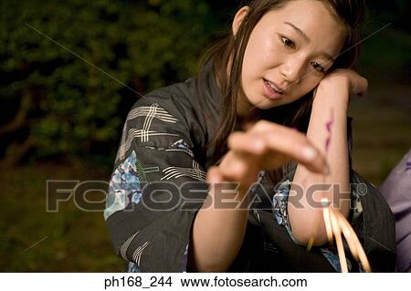 Picture - Young woman holding a sparkler. Fotosearch