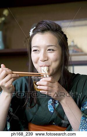 Young woman in kimono slurping on noodles View Large Photo Image Stock Photo - Young woman in kimono slurping on noodles. Fotosearch