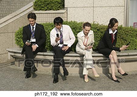 Group of executives looking at their mobile phones View Large Photo Image Stock Image - Group of executives looking at their mobile phones. Fotosearch
