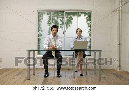 Stock Photography - Male executive and colleague sitting at table. Fotosearch