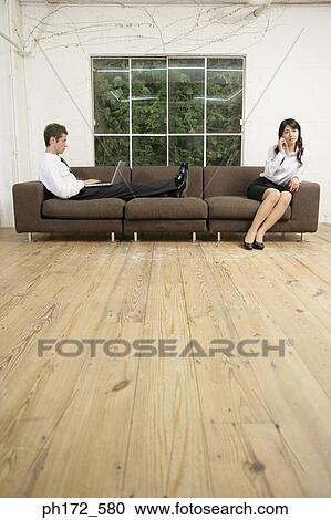 Male executive working on laptop and colleague holding a mobile phone View Large Photo Image Stock Image - Male executive working on laptop and colleague holding a mobile phone. Fotosearch