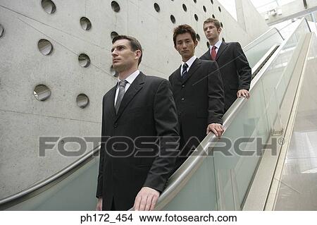 Three businessmen on escalator View Large Photo Image Picture - Three businessmen on escalator. Fotosearch