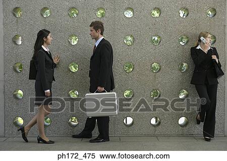 Three executives standing by wall View Large Photo Image Stock Photography - Three executives standing by wall. Fotosearch