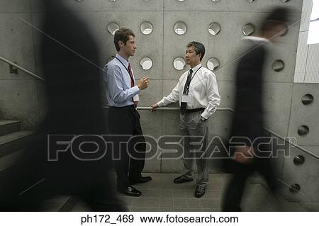 Two businessmen chatting by staircase View Large Photo Image Stock Photo - Two businessmen chatting by staircase. Fotosearch