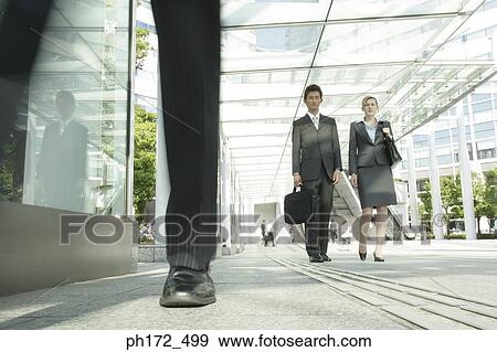 Two executives walking along pavement, low angle view View Large Photo Image Stock Photo - Two executives walking along pavement, low angle view. Fotosearch