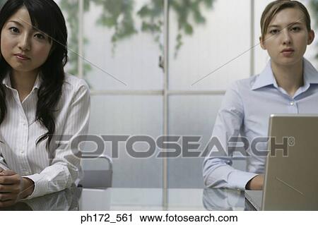Two female executives sitting at table, close-up View Large Photo Image Stock Image - Two female executives sitting at table, close-up. Fotosearch