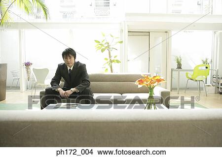 Well-dressed woman standing next to businessman sitting on sofa View Large Photo Image Picture - Well-dressed woman standing next to businessman sitting on sofa. Fotosearch