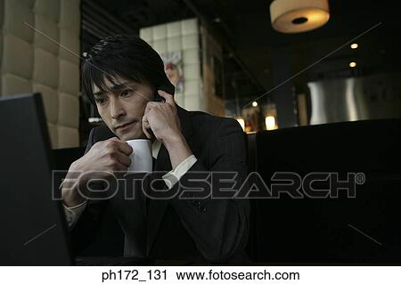 Stock Image - Businessman holding a cup and mobile phone. Fotosearch