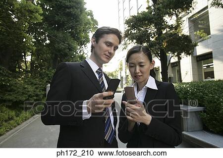Couple in suits holding mobile phones View Large Photo Image Stock Image - Couple in suits holding mobile phones. Fotosearch