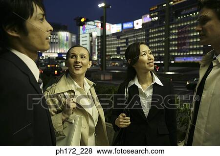 Stock Photo - Group of executives standing on the street at night. Fotosearch
