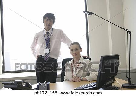 Male executive standing behind businesswoman View Large Photo Image Stock Photo - Male executive standing behind businesswoman. Fotosearch