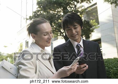Stock Image - Two executives with mobile phones, smiling. Fotosearch