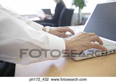 Stock Image - Close-up of male executive working on laptop. Fotosearch