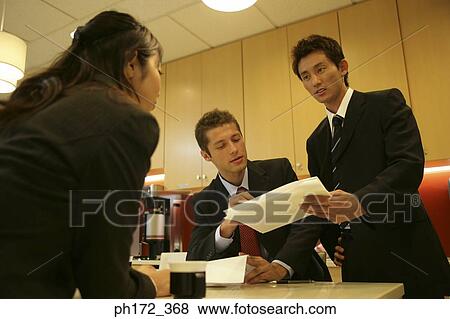 Stock Photo - Group of executives having a discussion, low angle view. Fotosearch