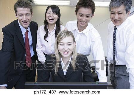 Stock Photo - Group of executives looking at computer, smiling. Fotosearch