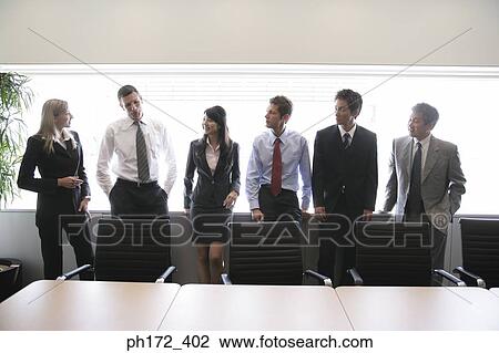Stock Image - Group of executives standing in board room. Fotosearch