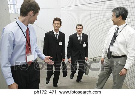 Stock Image - Group of male executives walking up staircase. Fotosearch