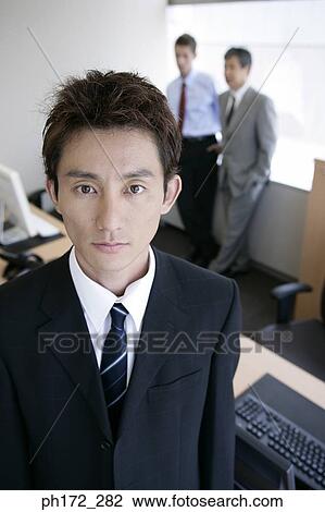 Portrait of male executive with colleagues standing in background, high angle view View Large Photo Image Stock Image - Portrait of male executive with colleagues standing in background, high angle view. Fotosearch