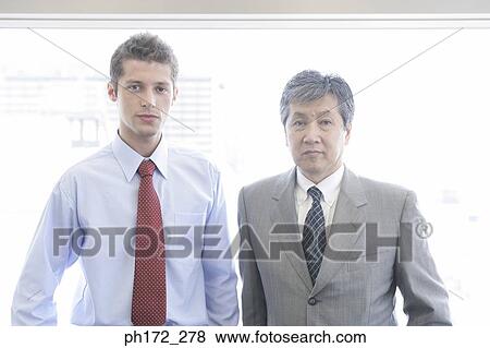 Stock Photo - Two male executives standing in office. Fotosearch