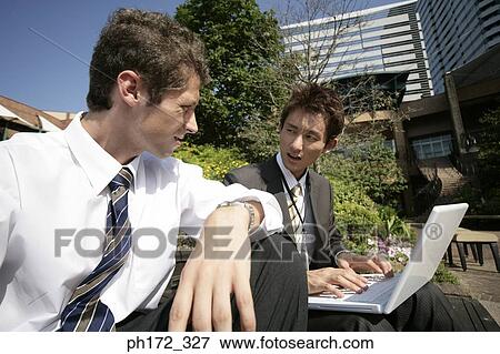Two male executives working on laptop View Large Photo Image Stock Photo - Two male executives working on laptop. Fotosearch