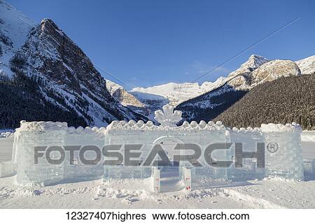 Stock Photograph - A beautiful ice castle with a Canadian flag has been carved from ice blocks and assembled on the frozen lake for skating and tourist photos at Fairmont Chateau Lake Louise and Banff National Park; Lake Louise, Alberta, Canada. Fotosearch