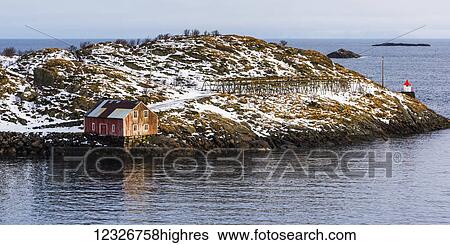 Stock Photograph - A building along the water's edge with a view of the ocean and horizon; Lofoten Islands, Nordland, Norway. Fotosearch