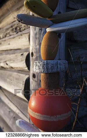 Stock Photograph - A colourful buoy hanging beside a log wall; Alaska, United States of America. Fotosearch