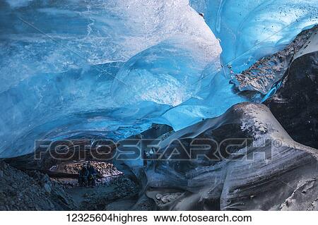 Stock Photograph - A couple poses for a picture inside a Canwell Glacier ice cave in the Alaska Range; Alaska, United States of America. Fotosearch