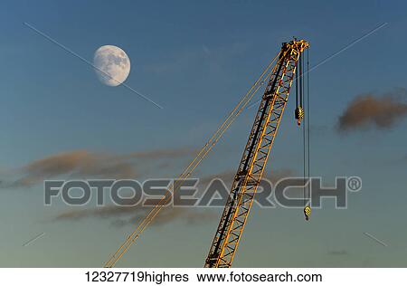 Stock Photograph - A crane in the sky with a moon; Sunderland, Tyne and Wear, England. Fotosearch
