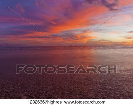 Stock Photograph - A dramatic beachscape with sunset colours of the sky and ocean taken in long exposure; Honolulu, Oahu, Hawaii, United States of America. Fotosearch