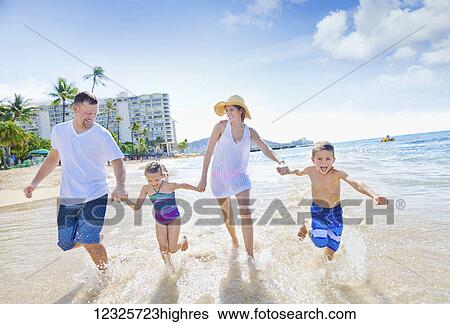 Stock Photograph - A family of four enjoying a summer vacation in Waikiki Beach; Honolulu, Oahu, Hawaii, United States of America. Fotosearch