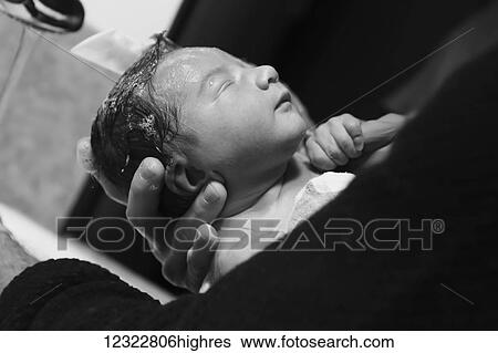 Stock Photograph - A father holds his newborn baby and washes his hair; Oregon, United States of America. Fotosearch
