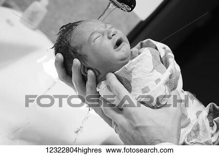 A father holds his newborn baby swaddled in a blanket and washing his hair under running water; Oregon, United States of America View Large Photo Image Stock Photograph - A father holds his newborn baby swaddled in a blanket and washing his hair under running water; Oregon, United States of America. Fotosearch