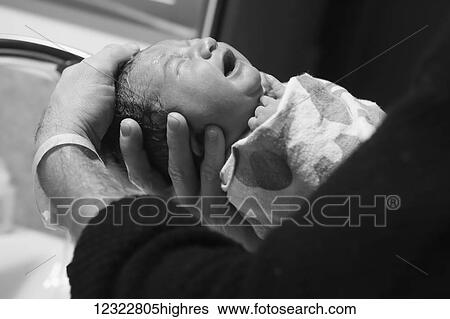 A father holds his newborn baby swaddled in a blanket and washes his hair; Oregon, United States of America View Large Photo Image Stock Photograph - A father holds his newborn baby swaddled in a blanket and washes his hair; Oregon, United States of America. Fotosearch