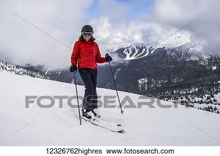 Stock Photograph - A female downhill skier poses for the camera on a ski hill at a ski resort; Whistler, British Columbia, Canada. Fotosearch