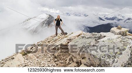 A female hiker poses alone for an adventurous portrait at the peak of a mountain on the hiking trails of Kicking Horse Mountain in the Rocky Mountains; British Columbia, Canada View Large Photo Image Stock Photograph - A female hiker poses alone for an adventurous portrait at the peak of a mountain on the hiking trails of Kicking Horse Mountain in the Rocky Mountains; British Columbia, Canada. Fotosearch