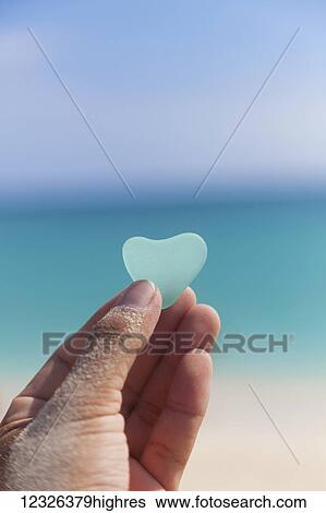 A hand holding a turquoise heart shaped sea glass against the background of the turquoise ocean; Honolulu, Oahu, Hawaii, United States of America View Large Photo Image Stock Photograph - A hand holding a turquoise heart shaped sea glass against the background of the turquoise ocean; Honolulu, Oahu, Hawaii, United States of America. Fotosearch